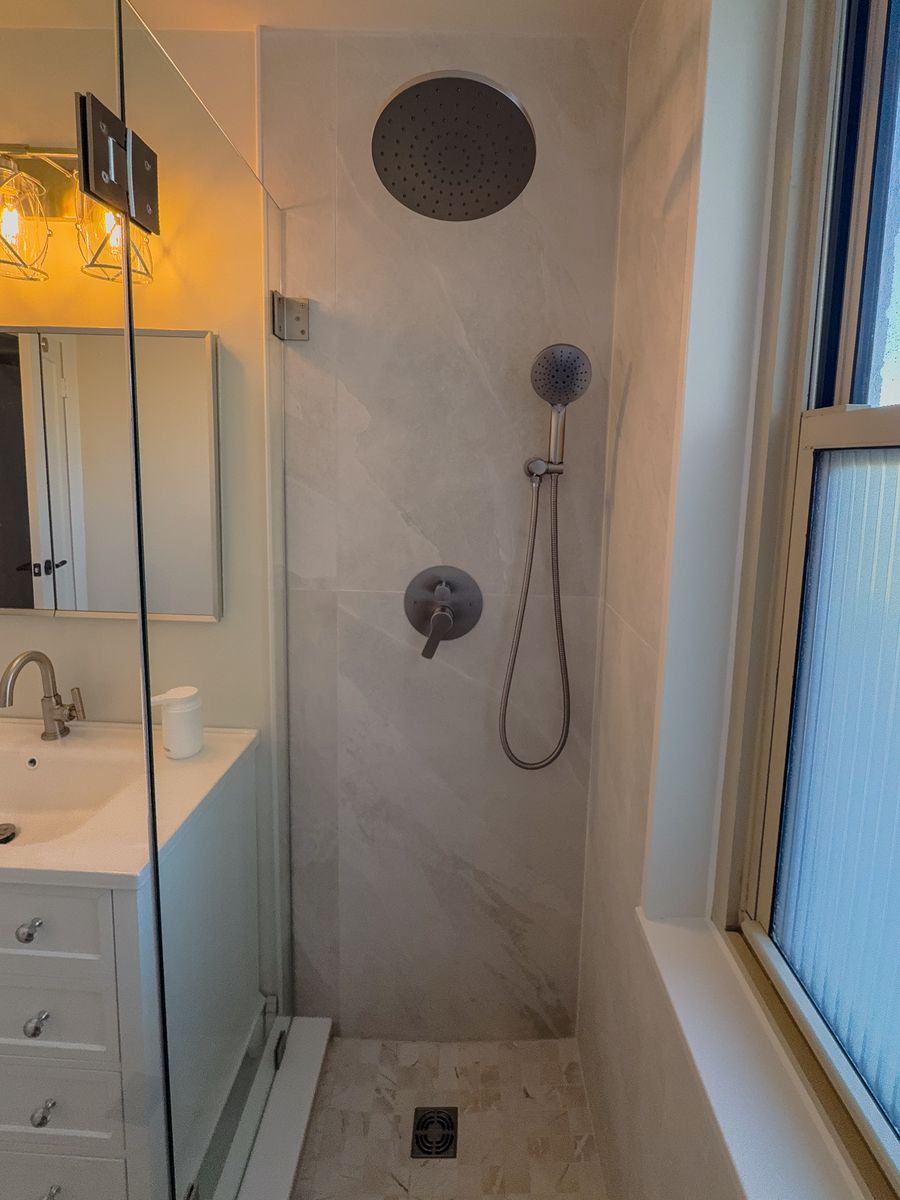 Walk-in shower with rain showerhead, handheld shower, and mosaic floor