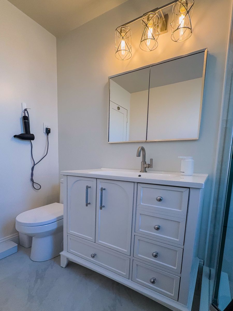 White vanity with drawers, medicine cabinet, and three-light fixture